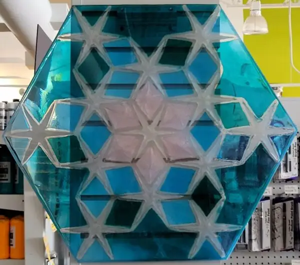 transparent blue resin hexagon surrounding thirteen 6-sided stars around a pink snowflake inside of 16 diamonds