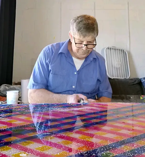 photograph of artist (me) using a Dremmel tool to trim edges of resin art painting